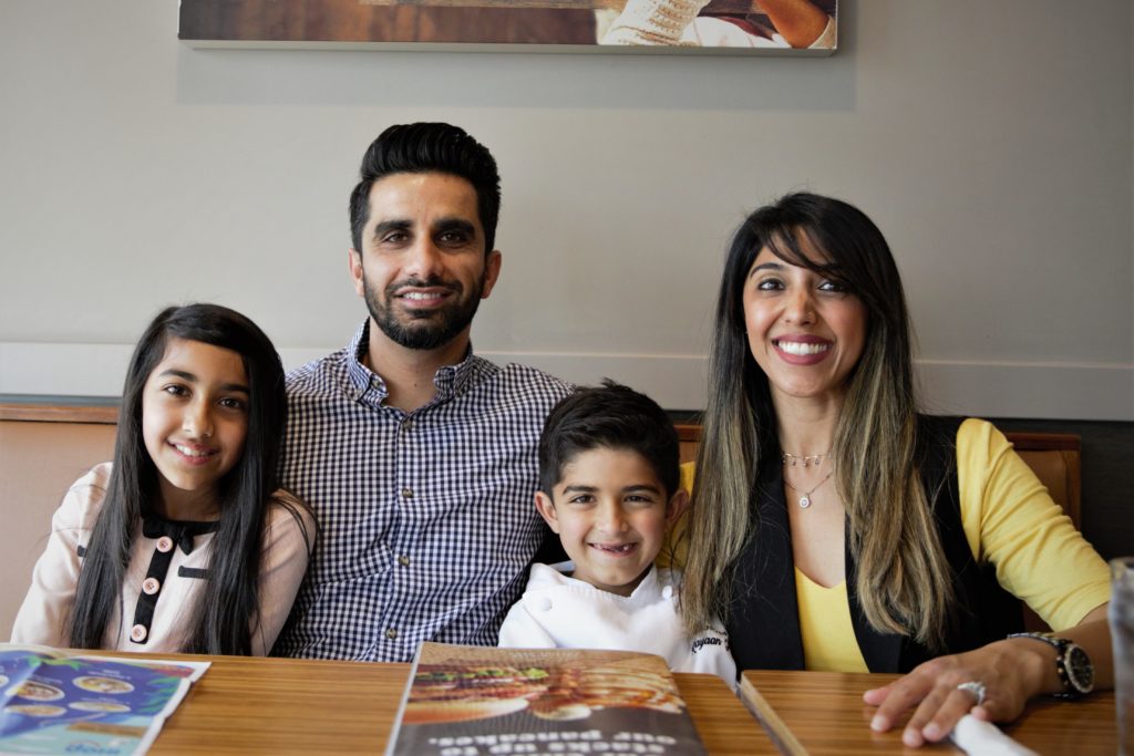 A portrait of the Kalhoro family, which includes Rayaan with his mom, dad and older sister.