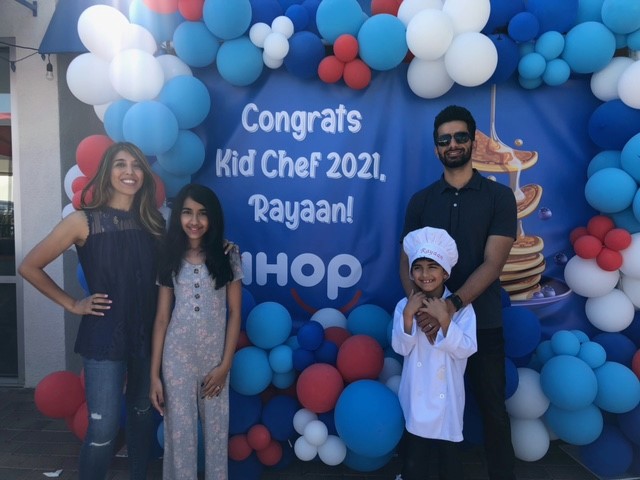 The Kalhoro Family in front of IHOP Kid Chef congratulatory sign