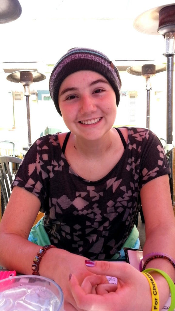 Lauren Aslanian, in a knit cap, sitting at a table and smiling. 